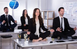 Young and mindful business leaders sitting on desk meditating in office