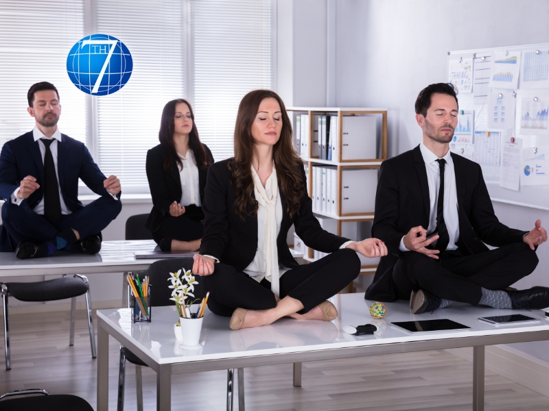 Young and mindful business leaders sitting on desk meditating in office