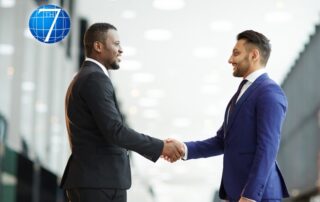 Two young intercultural delegates in suits demonstrating conflict resolution by shaking hands while greeting one another before a meeting or summit.