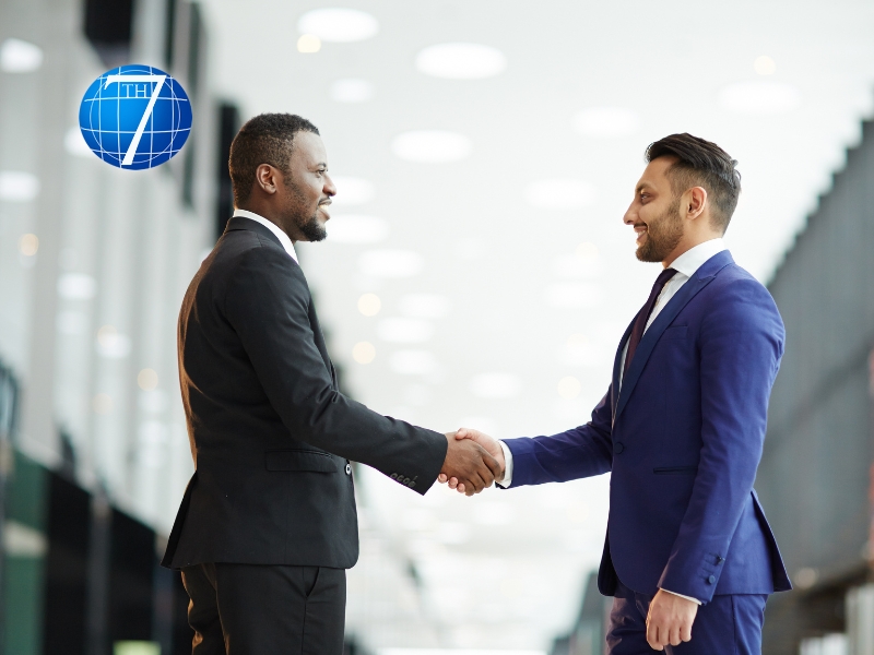 Two young intercultural delegates in suits demonstrating conflict resolution by shaking hands while greeting one another before a meeting or summit.