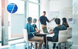 Group of professionals in a modern office engaged in a strategic planning session, with a leader presenting ideas on a whiteboard. The session emphasizes storytelling as a method to develop strategic thinking skills within the team.