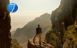 A leader stands on a rocky peak overlooking a vast valley, embodying patience in leadership and the strength to navigate challenges with calm and reflection.