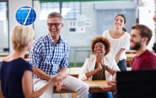 A group of diverse professionals laughing and engaging in a discussion in a bright office space, symbolizing collaboration, leadership, and community impact.