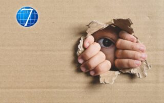 An image symbolizing curiosity, featuring a child's eye and hands peeking through a torn cardboard hole, representing exploration and the desire to discover.